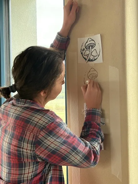 Denisa Divoká nanáší šablonu na hliněnou stěnu